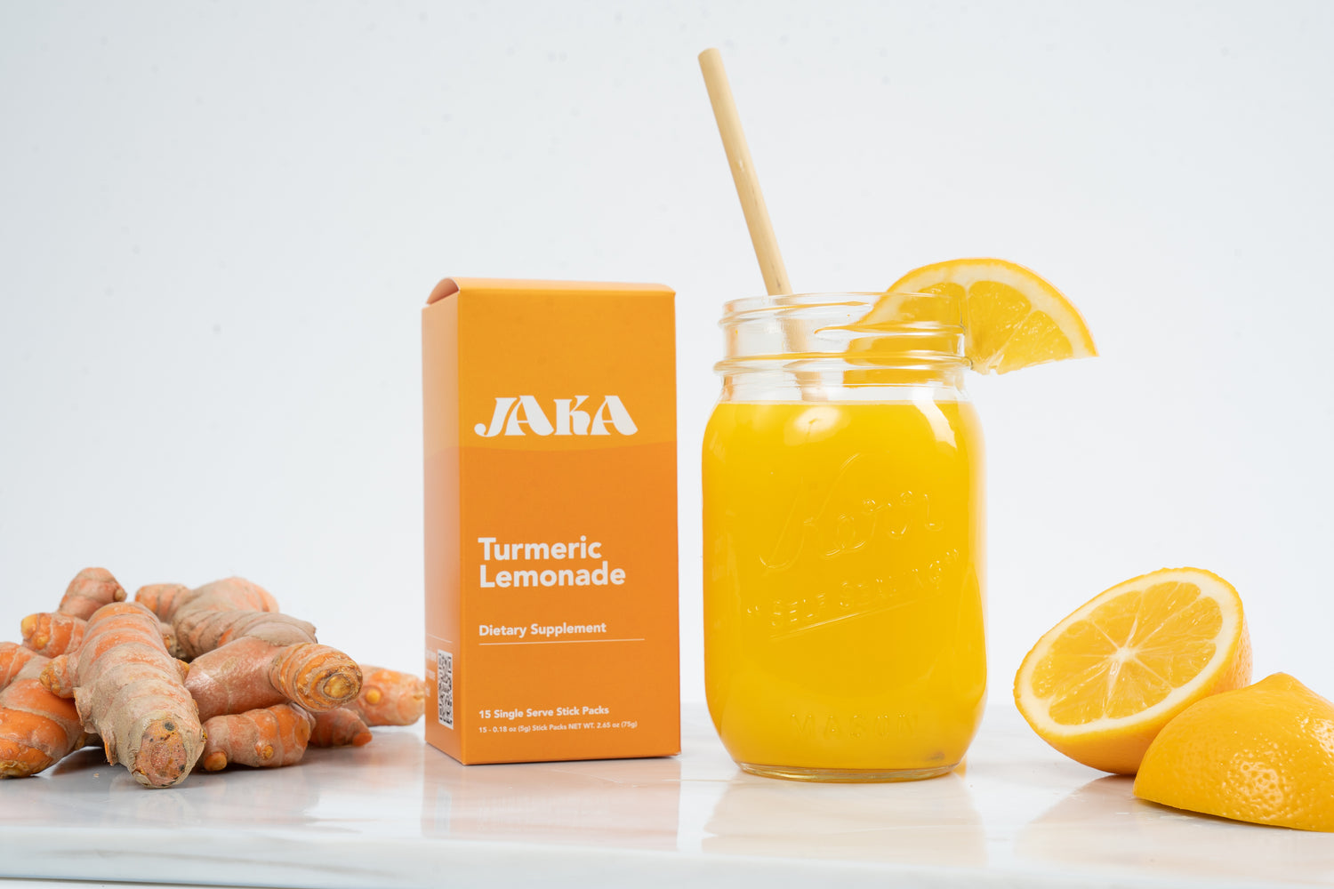 Jaka turmeric lemonade box with turmeric, lemons and a glass of jaka turmeric lemonade